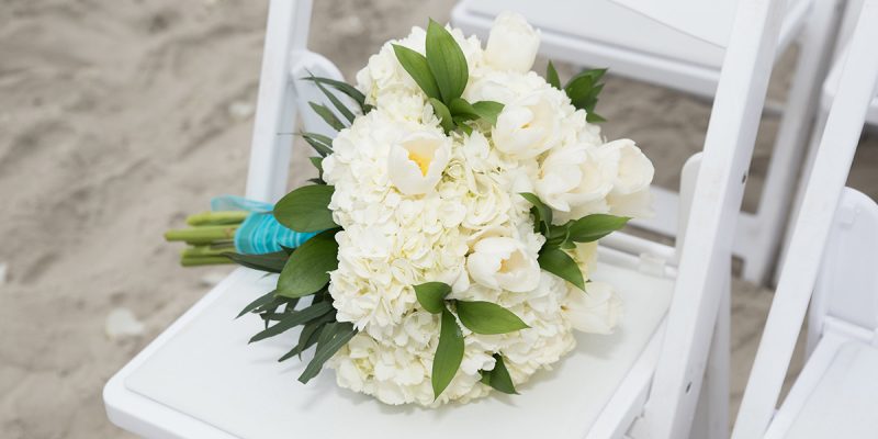 EIR_Weddings_Headers_1200x600_Testimonials Beach wedding setup white flowers on white chair in emerald isle nc